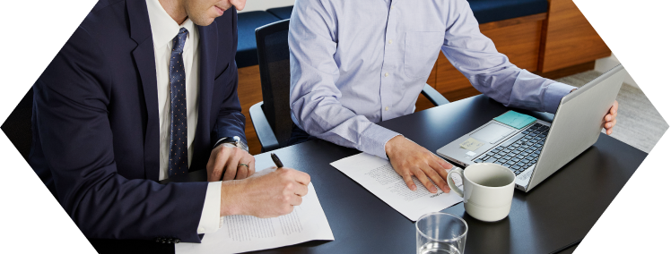 Two employees in a meeting taking notes